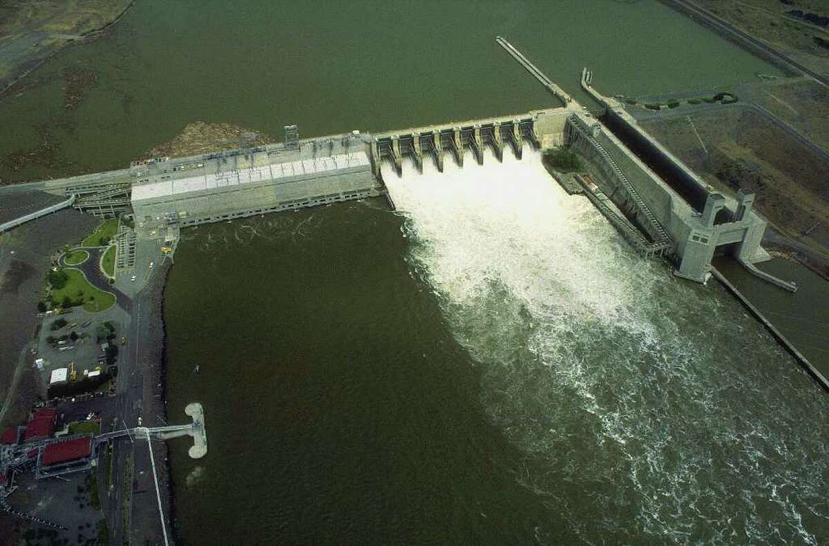 An aerial view of Lower Monumental Dam on the Snake River in Washington. Fish ladders can be seen on either side of the dam - one alongside the locks at right, and one snaking up the wall at left.