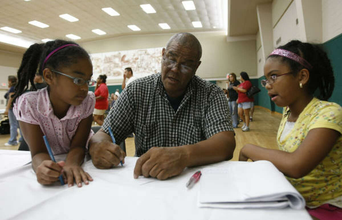 Joseph Broussard fills out a contract at the Nessler Center as daughters Galilea, 9, left, and Gabriela Maria, 11, help him recall health problems he has experienced.