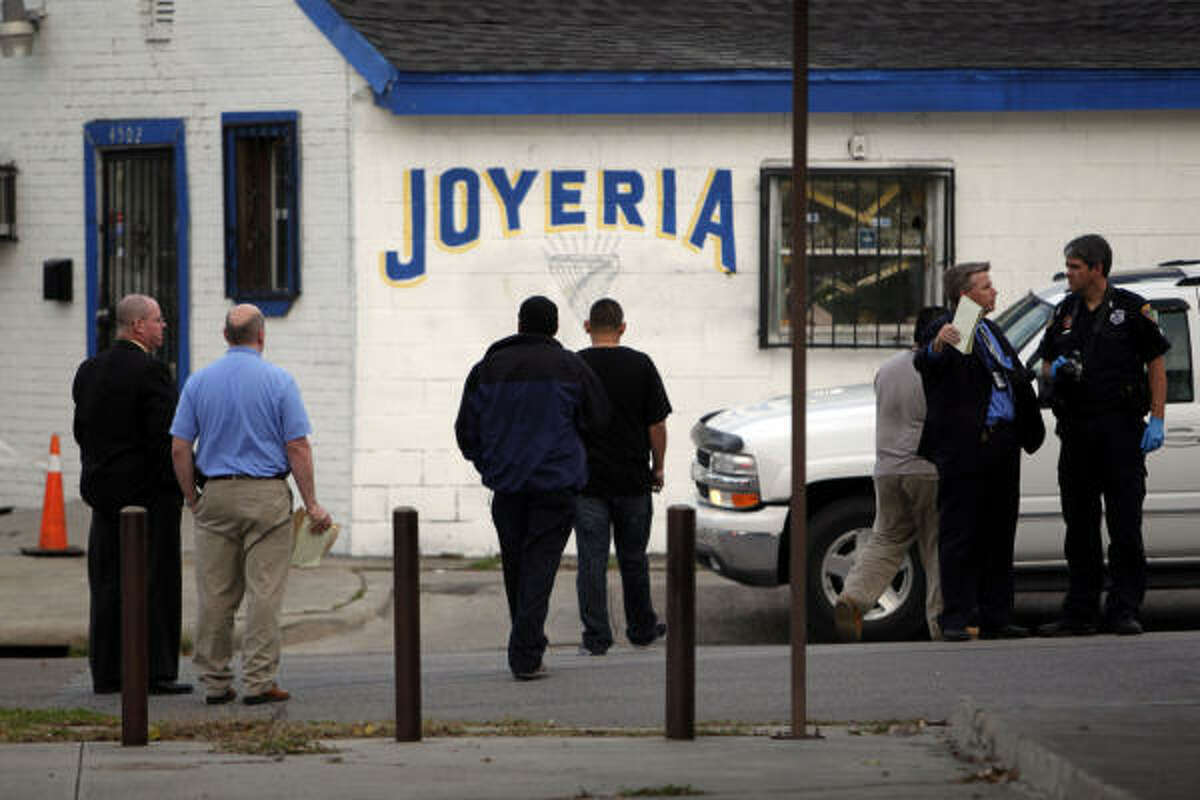 Police officers and detectives investigate the shooting of three suspected robbers by a jewelry store owner at his store east of downtown Houston Thursday, Dec. 16, 2010.
