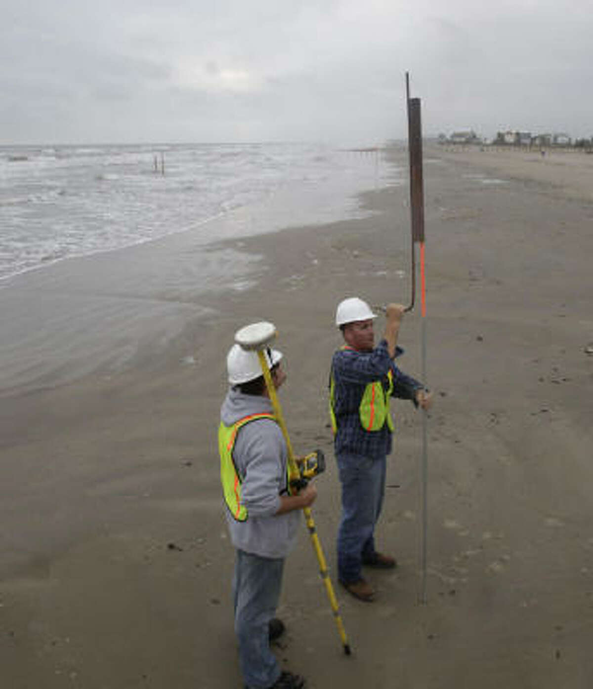 Matt Radosz, left, and Joni Hershberger, both of Weeks Marine, a contractor hired by the General Land Office, put down markers along the beach on Galveston Island.