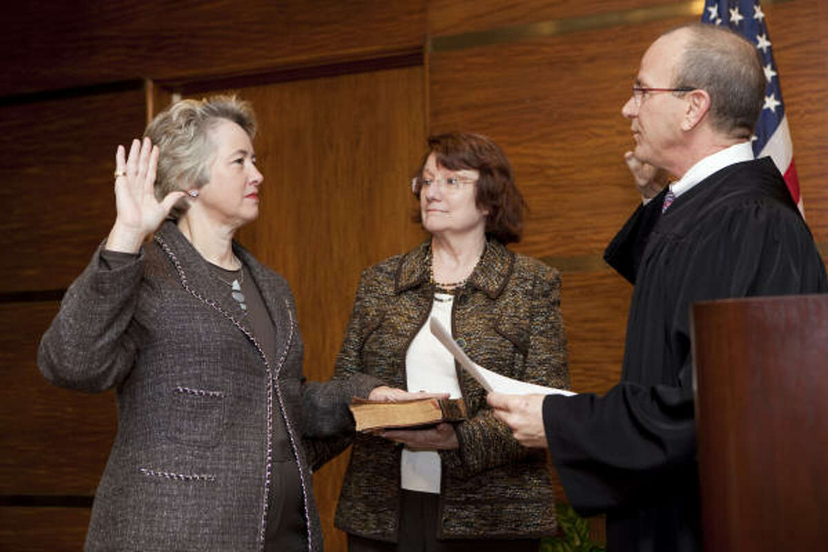 Mayor Annise Parker gets sworn in with her grandparents’ Bible, shown being held by Parker's partner, Kathy Hubbard, on Saturday. State District Judge Steven Kirkland administers the oath.