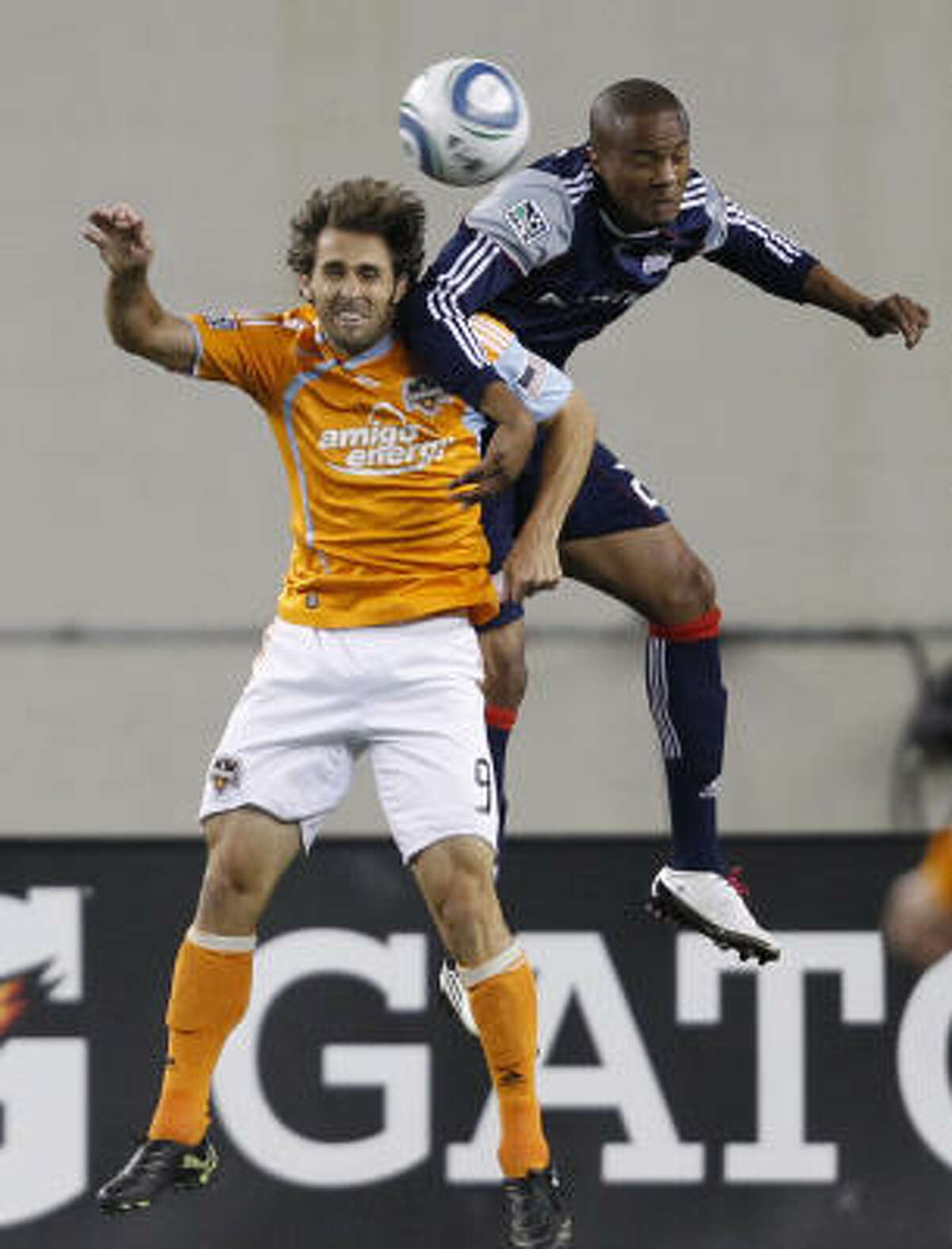 Dynamo midfielder Brian Mullan and Revolution defender Darrius Barnes battle for the ball.