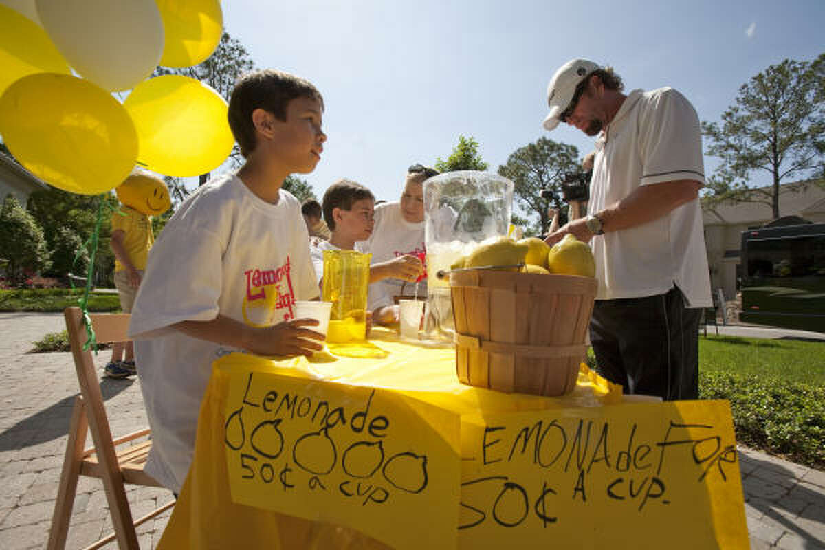 Ryder Hammond, left front, 11, and his twin brother, Wyatt, serve Astro legend Jeff Bagwell a glass of lemonade at a stand they put up in front of one of John Daugherty Realtors' listed properties Sunday in Bellaire.