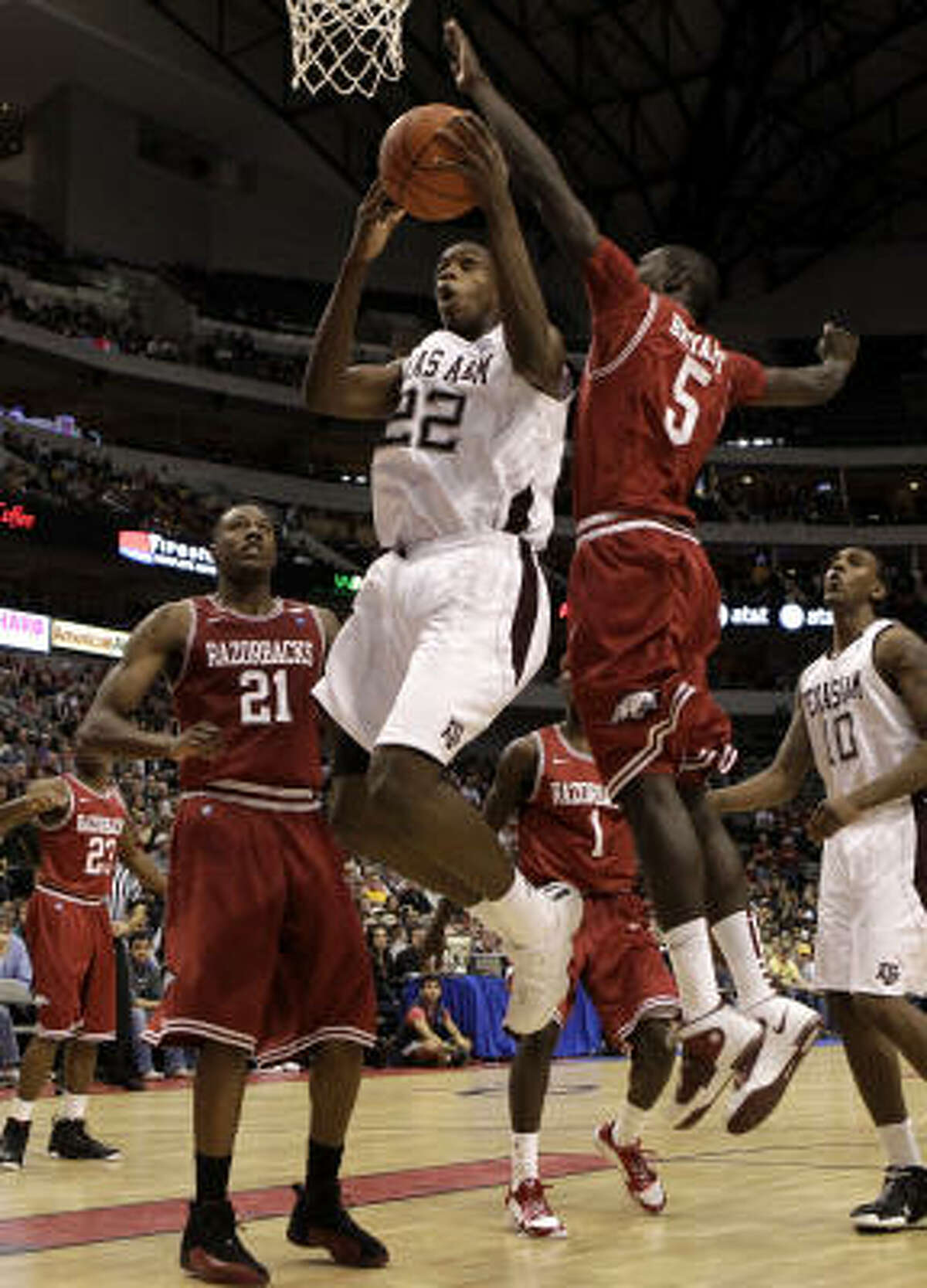 Texas A&M forward Khris Middleton drives to the basket past Arkansas forwards Delvon Johnson (21) and Glenn Bryant (5).
