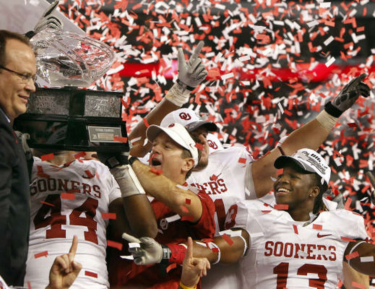 Oklahoma coach Bob Stoops, center, and his players celebrate with the Big 12 championship trophy.