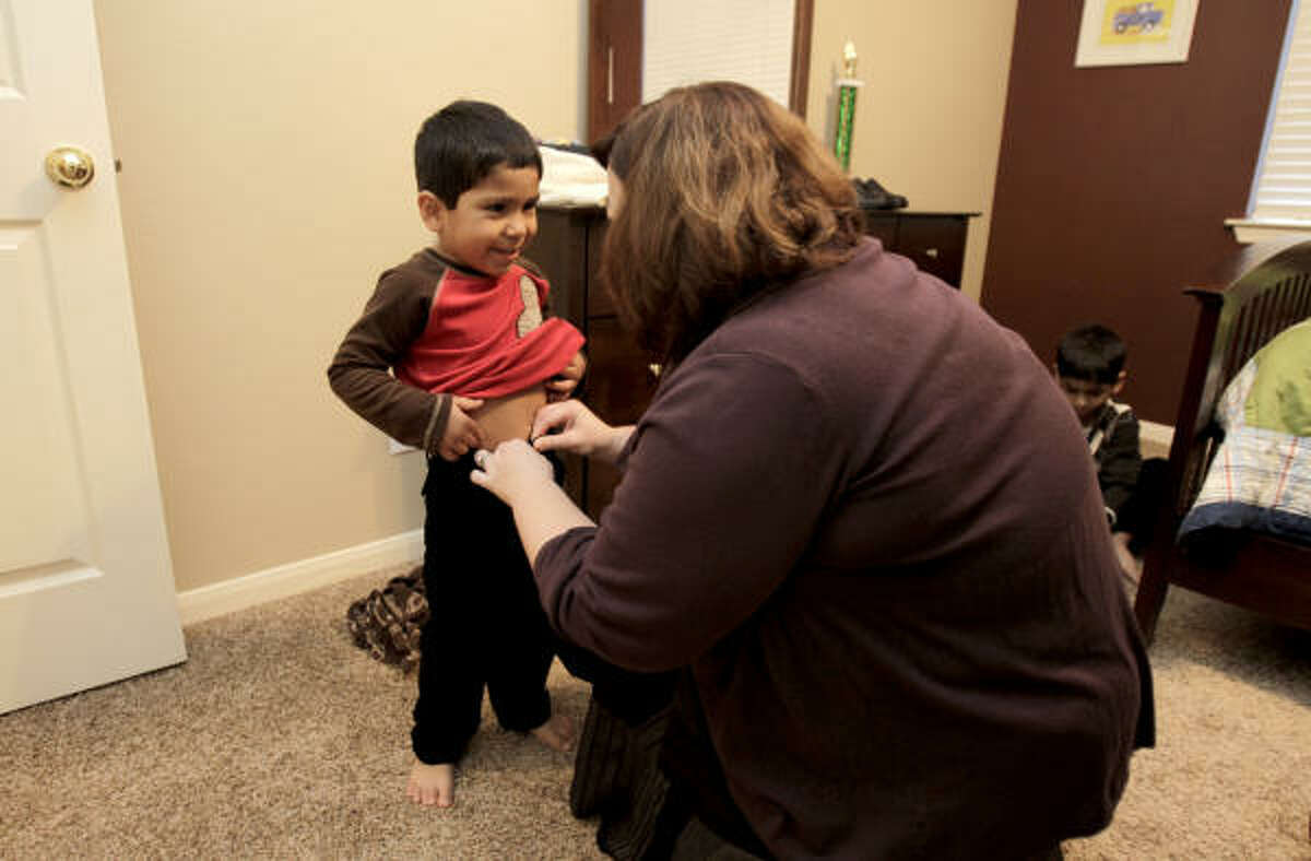 Rebecca Albus, right, zips up the pants of her soon-to-be-official son, Jonathan, 5, as the family got ready at their Katy home to make the drive to the Harris County Juvenile Justice Center to take part of National Adoption Day. The Albus' adopted Jonathan and his 7-year-old biological brother Angel. The boys have lived with the couple since September 2009.