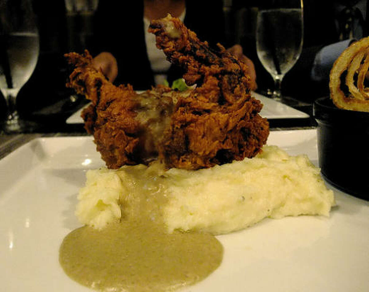 Buttermilk fried game hen with chicken-liver gravy at Voice, in the Hotel Icon. On the side is a cast-iron mini casserole of collard greens.