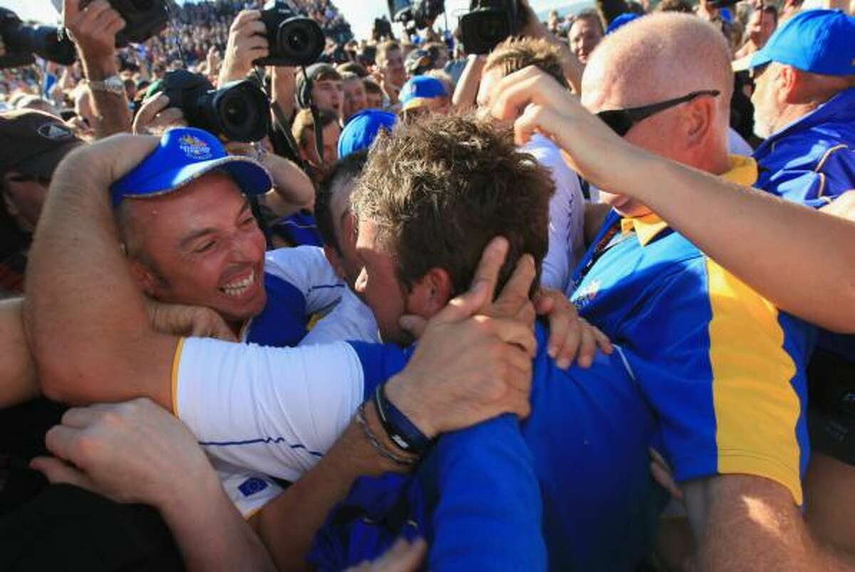 Graeme McDowell of Europe is mobbed by his teammates and caddies after the decisive hole.
