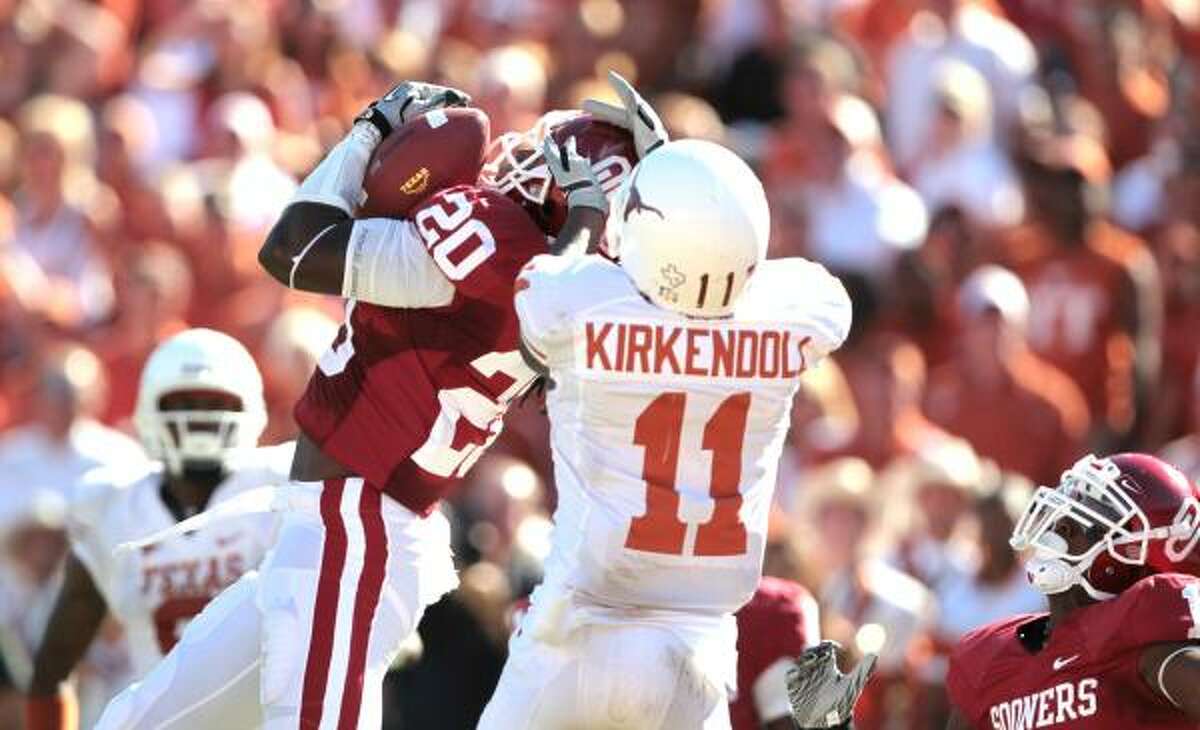 Sooners cornerback Quinton Carter (20) gets an interception while Texas wide receiver James Kirkendoll attempts to bring him down.