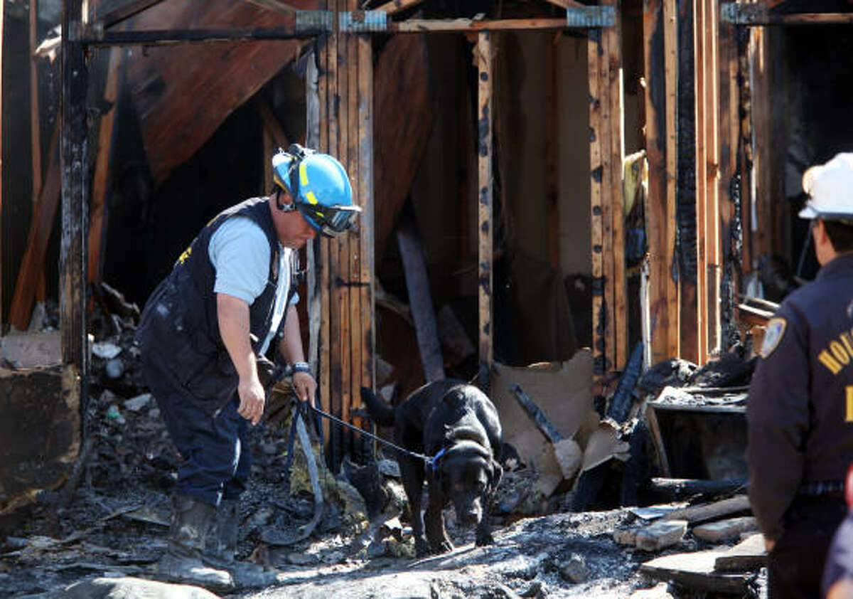Arson Investigator walks the dog through the debris in efforts to find missing elderly couple after two alarm fire broke out at the Greenhouse Patio apartments in Houston, TX. Firefighters extinguished the blaze, and stabilized the building to search for the elderly couple.