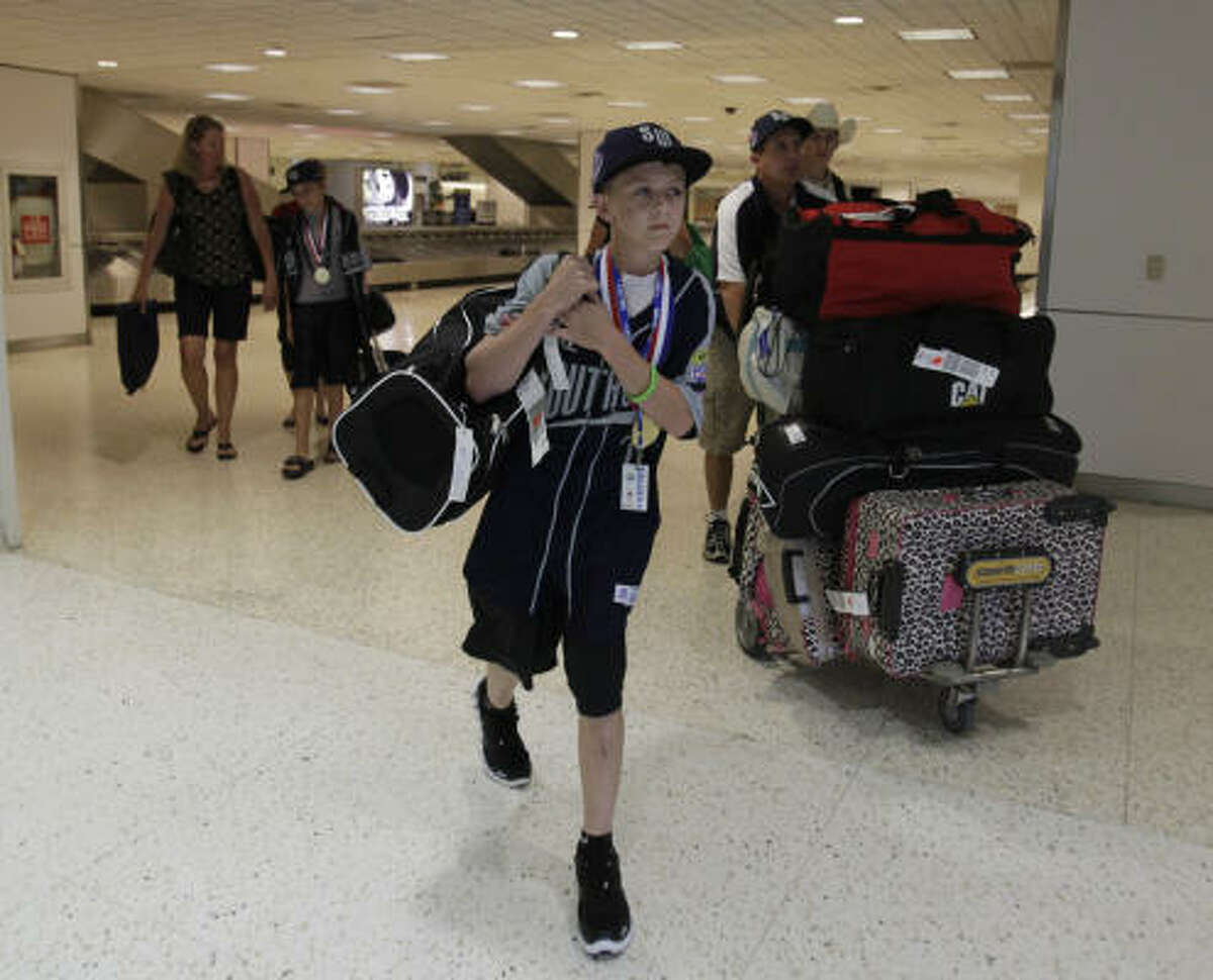 Hunter Smith walks with his dad, Don, out of the airport after he and the other Pearland Little Leaguers returned home to Houston from South Williamsport, Pa. Pearland's run in the Little League World Series ended with a loss to Taiwan in the consolation game.