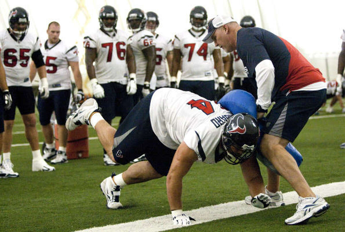 Texans assistant offensive line coach Frank Pollack runs guard Kasey Studdard through a blocking drill during Monday's practice at training camp.