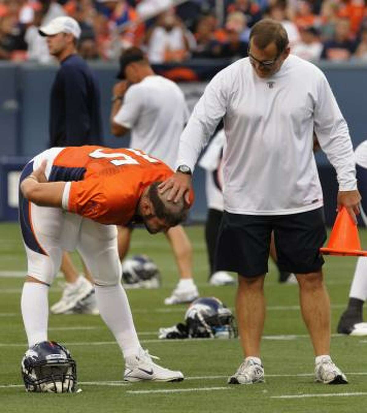 Denver Broncos strength and conditioning coach Rich Tuten, right, touches the new haircut on rookie quarterback Tim Tebow on Aug. 7.
