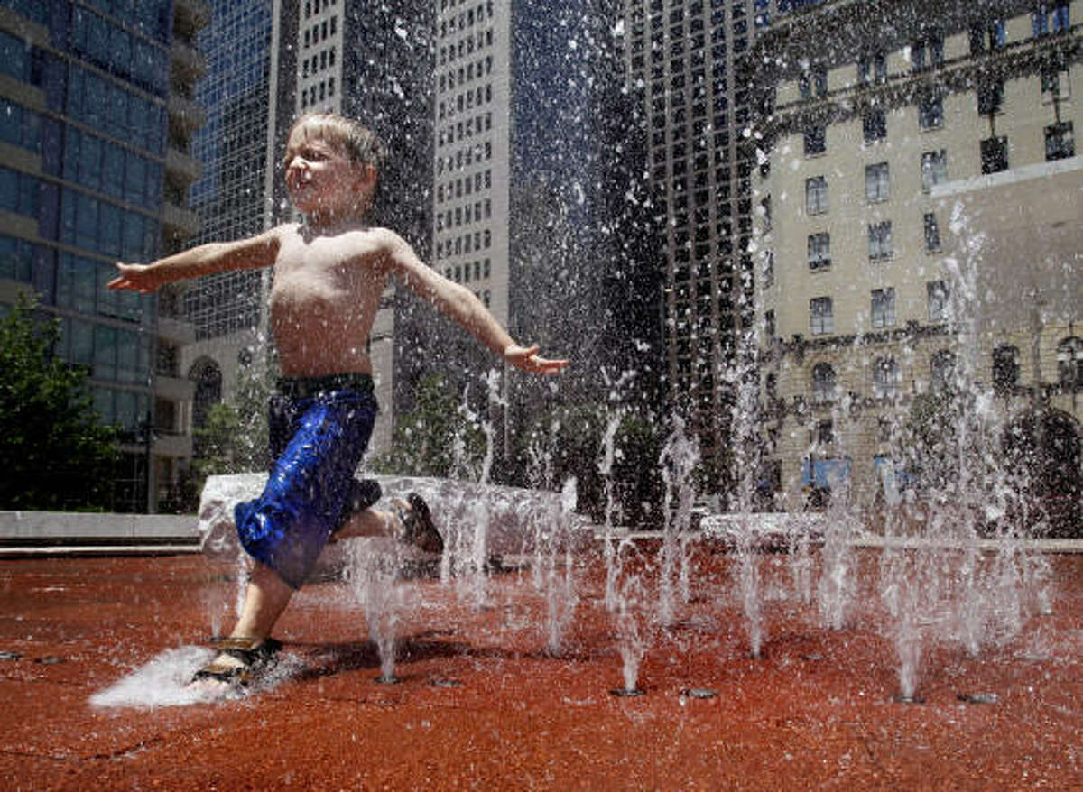 Sam Posey, 4, runs through fountains at Main Street Garden Park in downtown Dallas where temperatures reached into the triple digits.