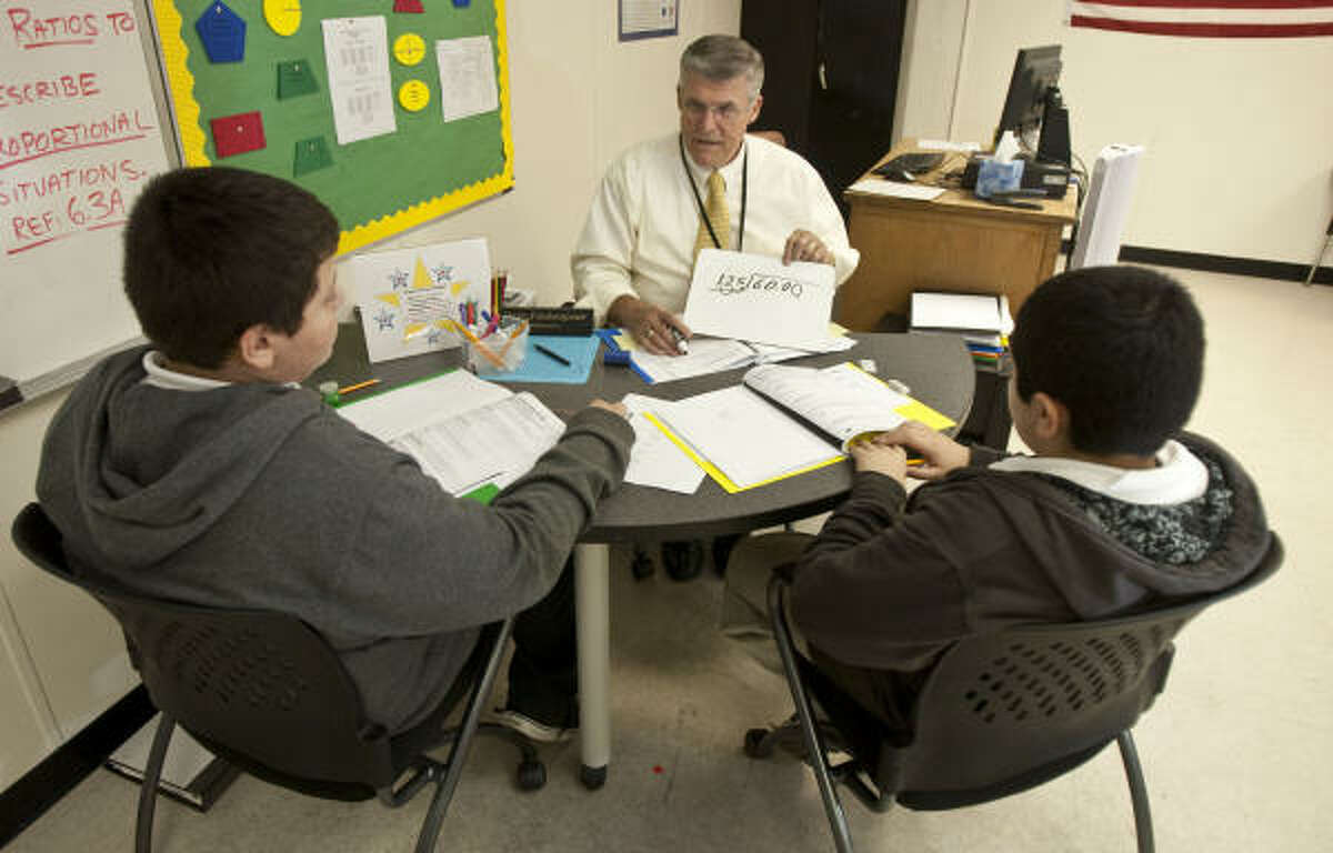 Math tutor David Fashenpour, center, explains a math equation during a lesson with Cristian Garcia, 12, left, Fernando Vera, 11, at Dowling Middle School. Fashenpour is on his third career as a tutor as part of the Apollo 20 program.