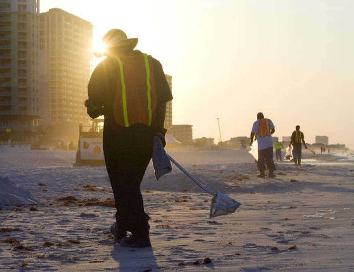 As the sunrises at Pensacola Beach, British Petroleum clean up crews walk along the shore looking for and cleaning up small bits of oil debris from the Deepwater Horizon oil spill in Pensacola, Florida.