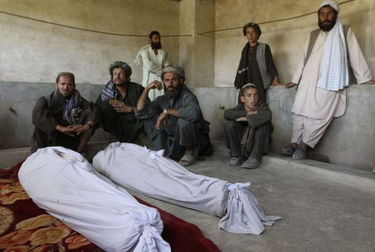 Afghan men stand around the bodies of people killed in a blast in Kandahar's Argandab district Thursday, June 10, 2010. NATO blamed the Taliban for the suicide attack that killed at least 40 Afghan wedding guests in an area where U.S.-led troops are massing to drive insurgents from their fiefdom. Officials said a suicide bomber strapped with explosives had walked into on June 9 wedding party -- which relatives said was attended by members of an anti-Taliban militia -- and unleashed a deadly hail of ballbearings. At least 40 killed in Taliban suicide bombing at wedding in Afghanistan