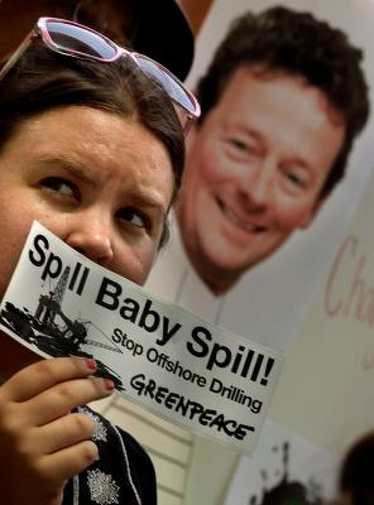A young woman holds a sticker up while joining about 50 demonstrators with hand-made signs with the image of BP CEO Tony Hayward while protesting the company's handling of the oil spill.