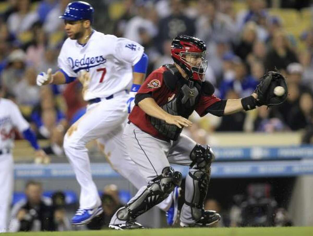 Dodgers' James Loney, left, scores after tagging up on a sacrifice fly by Jamey Carroll as catcher Humberto Quintero, right, gets a late throw during the fourth inning.