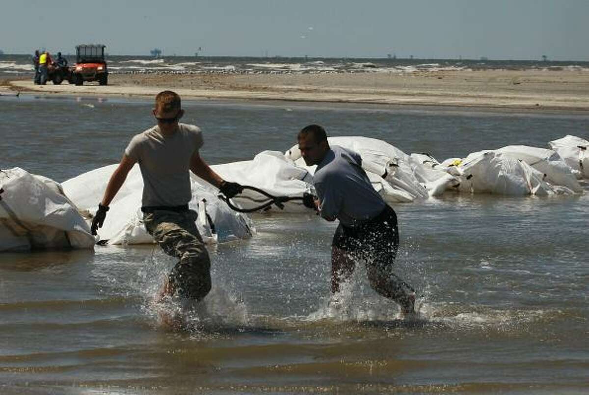 Louisiana National Guard members retrieve a sling load cable as helicopters drop sand bags into place as they create a barrier in an attempt to protect an estuary from the massive oil spill on May 10, 2010 in Lafourche Parish, La.