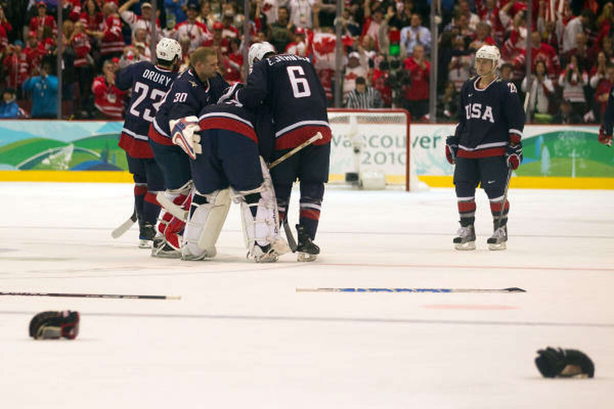 Team USA goalie Ryan Miller is consoled by Tim Thomas (30) and Erik Johnson (6) after he gave up the game-winning goal in overtime.