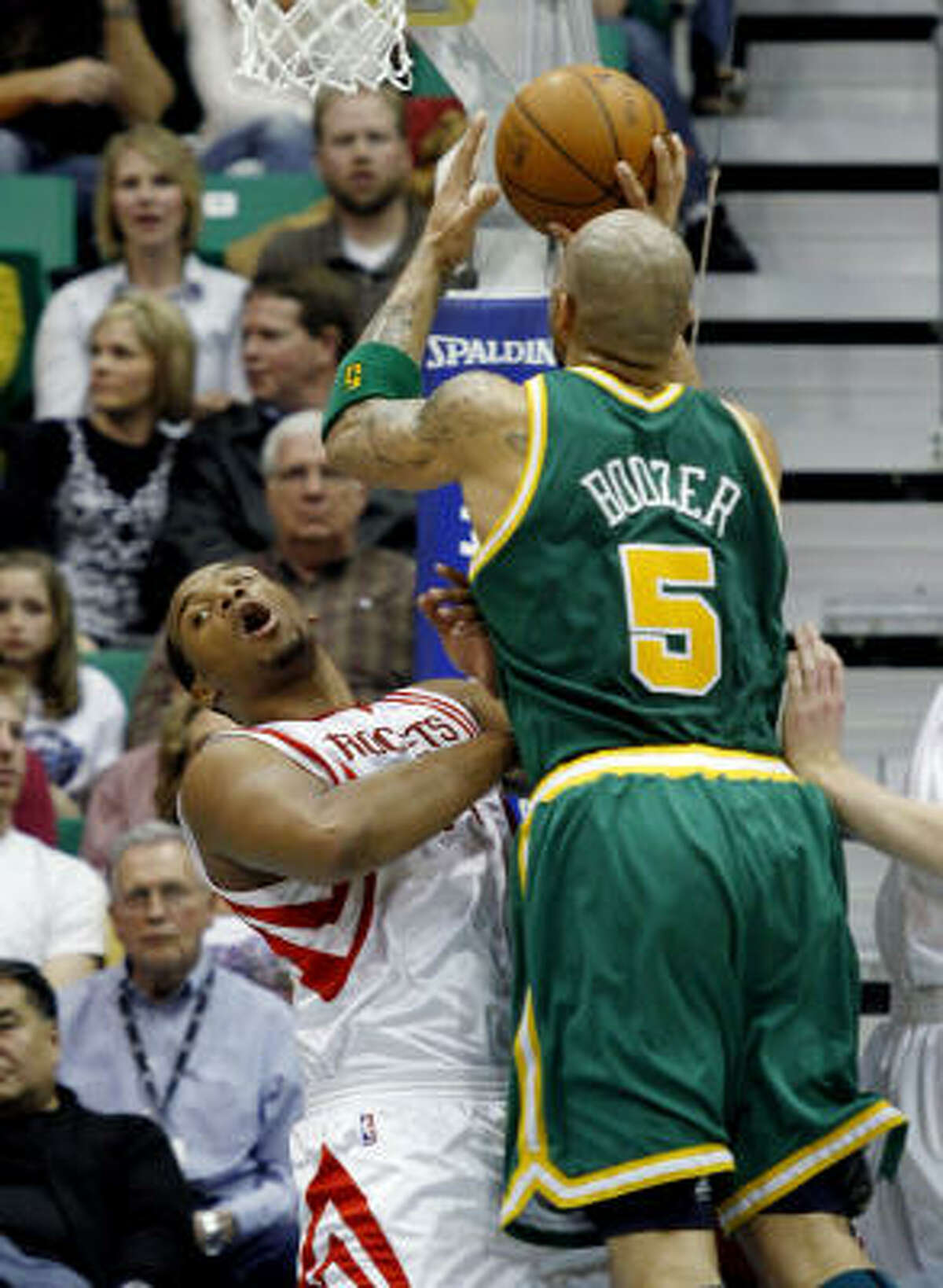 Rockets forward Chuck Hayes, left, is knocked to the floor by Jazz forward Carlos Boozer on a drive to the basket in the first half.