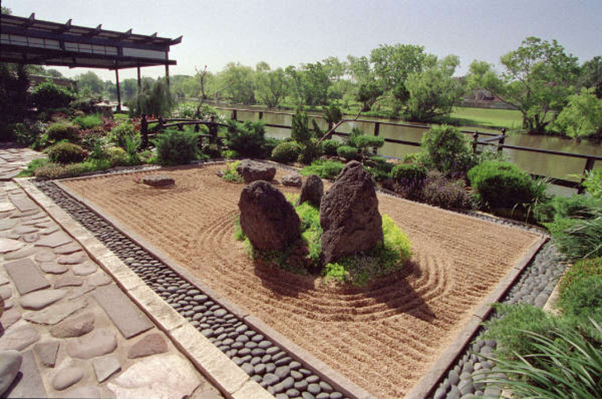 In this Terry Vekris-designed Zen garden, a rectangular bed of raked gravel is edged in polished limestone and blue-black moonrock. The gravel, representing a body of water, is raked into calming straight lines and in concentric circles, representing rippling movement around an “island” of low-growing juniper and three boulders. The cool, smooth moonstones flow around the perimeter like a river.
