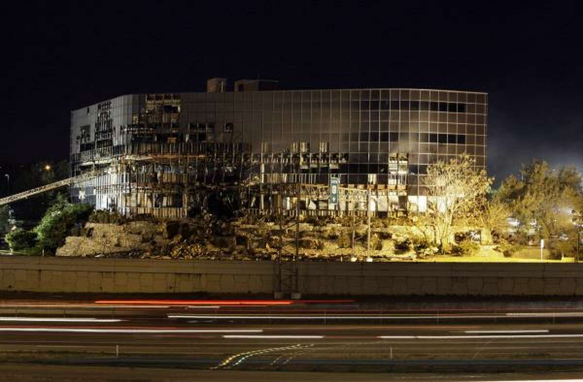 Streaks of light from vehicle traffic are shown in front of the damaged building.