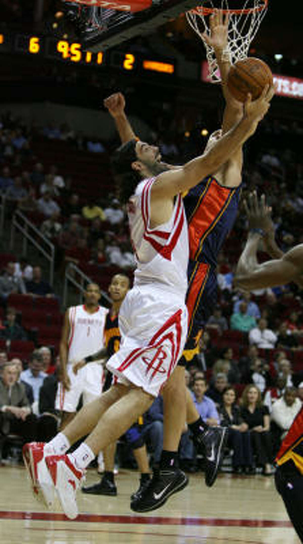 Rockets forward Luis Scola goes up for a reverse layup while Warriors center Andris Biedrins attempts to defend.