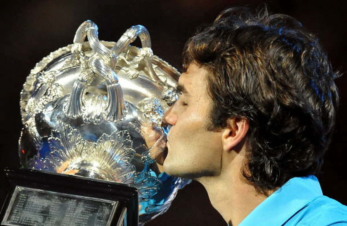 Roger Federer kisses the trophy for the 16th time in a Grand Slam in his 22nd appearance in a Grand Slam final.