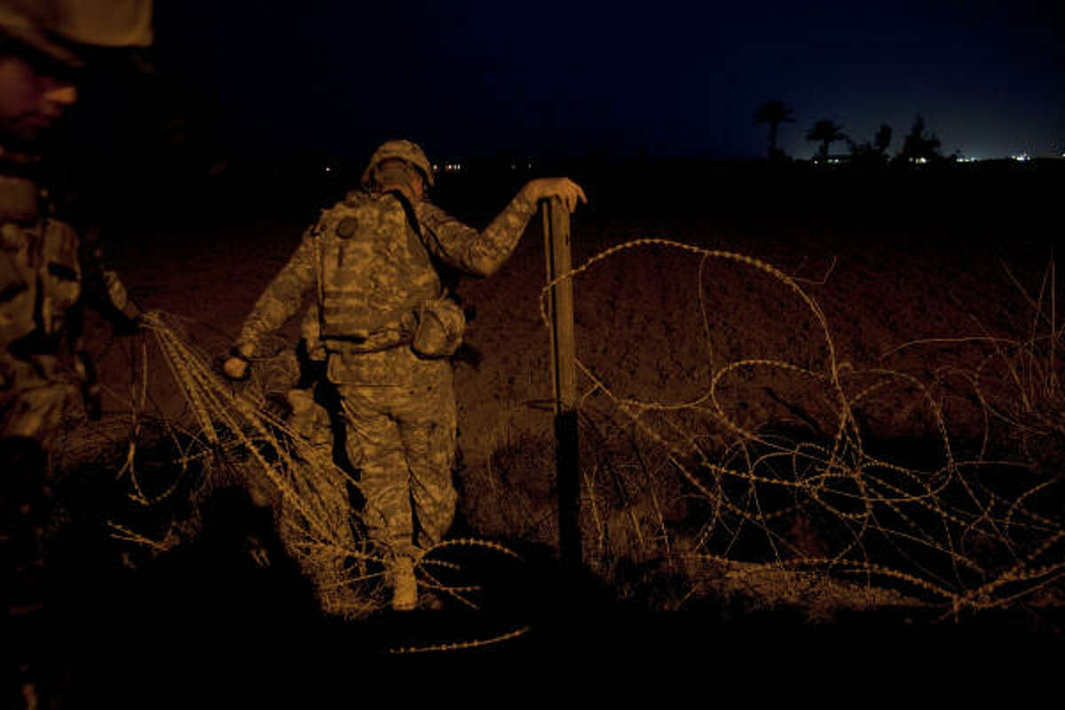 Soldiers from the 72nd Infantry Brigade Combat Team climb through razor wire to begin a pre-dawn foot patrol mission in Baghdad, Iraq. The 72nd Infantry Brigade Combat Team's Quick Response Force in Camp Cropper surveyed the perimeter of exterior wall for any tampering.
