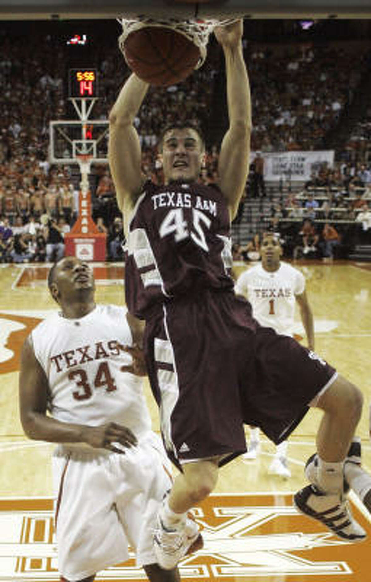 Texas A&M forward Nathan Walkup dunks in front of Texas center Dexter Pittman during the first half of Saturday's matchup in Austin.