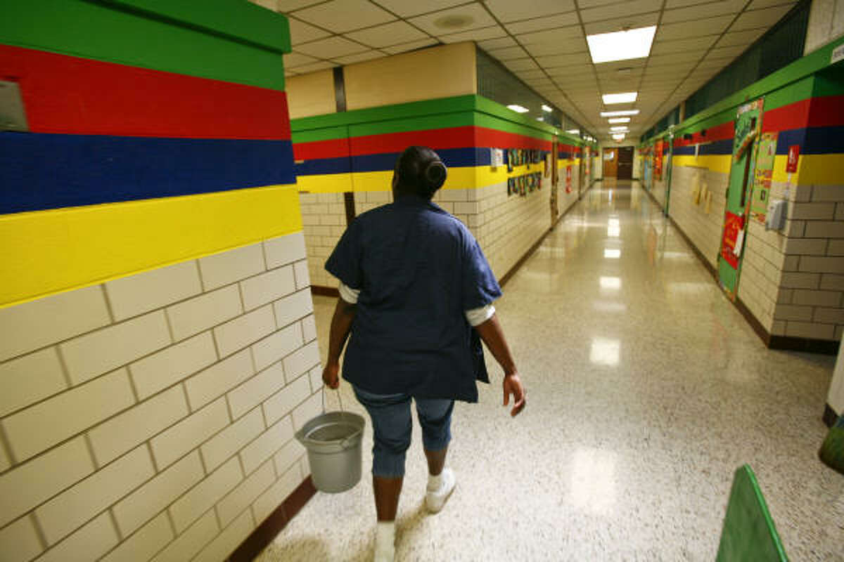 Carrie Miller walks through the empty hallways with a bucket of disinfectant at Mary McAshan Gibbs Pre-K Center on Tuesday in Huntsville after local schools shut down temporarily.