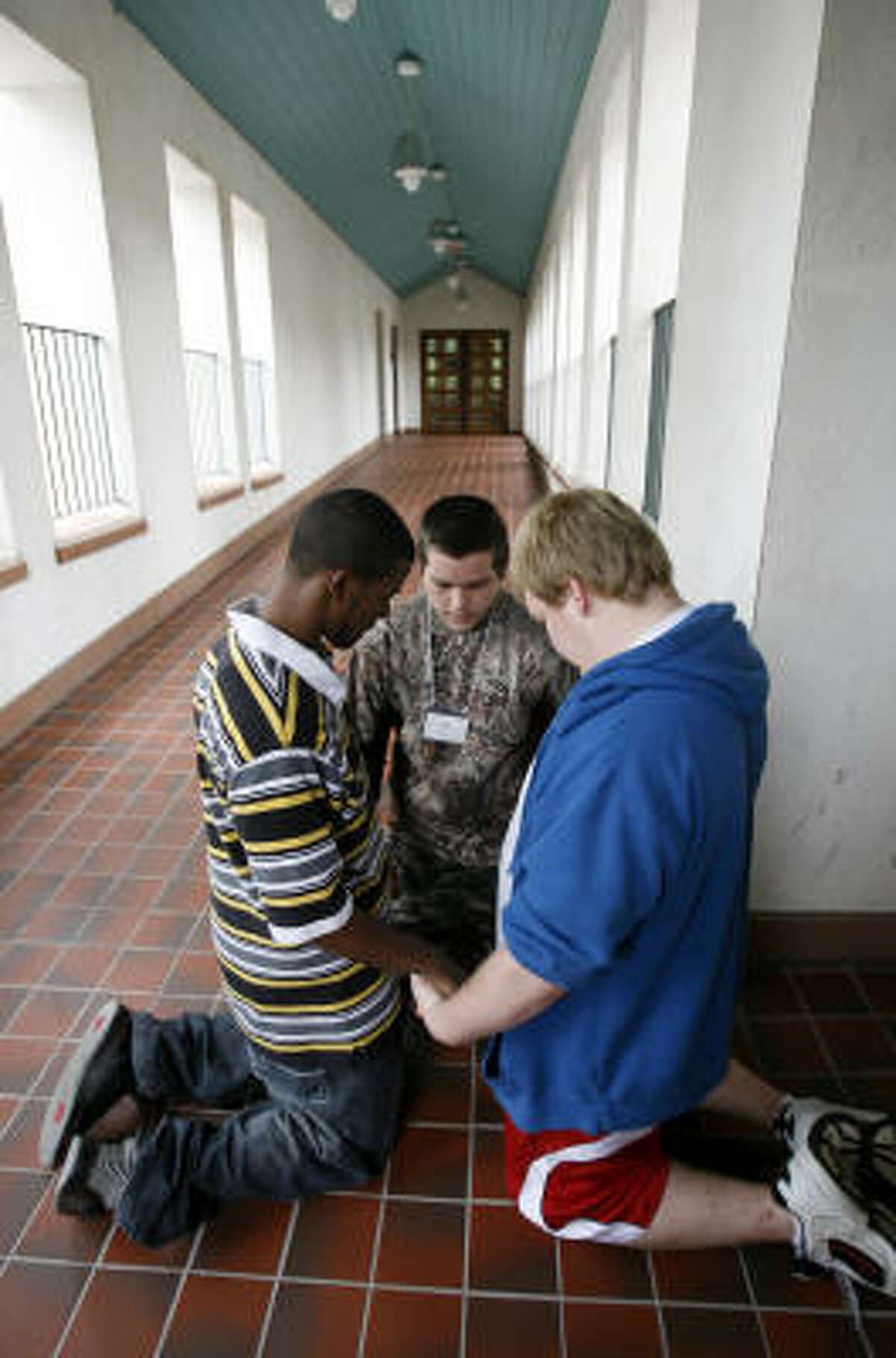 Clay Benton, 18, center, prays with his friends Terrence Payton, 18, left, and Zach Thomas, 17.﻿