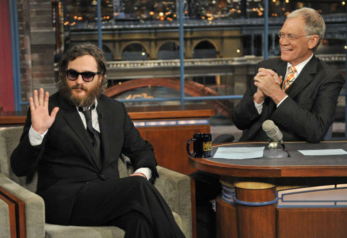 Actor Joaquin Phoenix, left, waives to the audience from the set of "The Late Show with David Letterman," in New York on Wednesdayas host David Letterman watches from the desk.