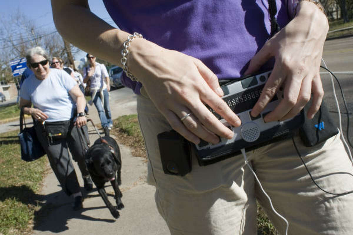 Jamie Adams, right, demonstrates a GPS product for the visually impaired to Bernice Klepac and her guide dog Niobe.