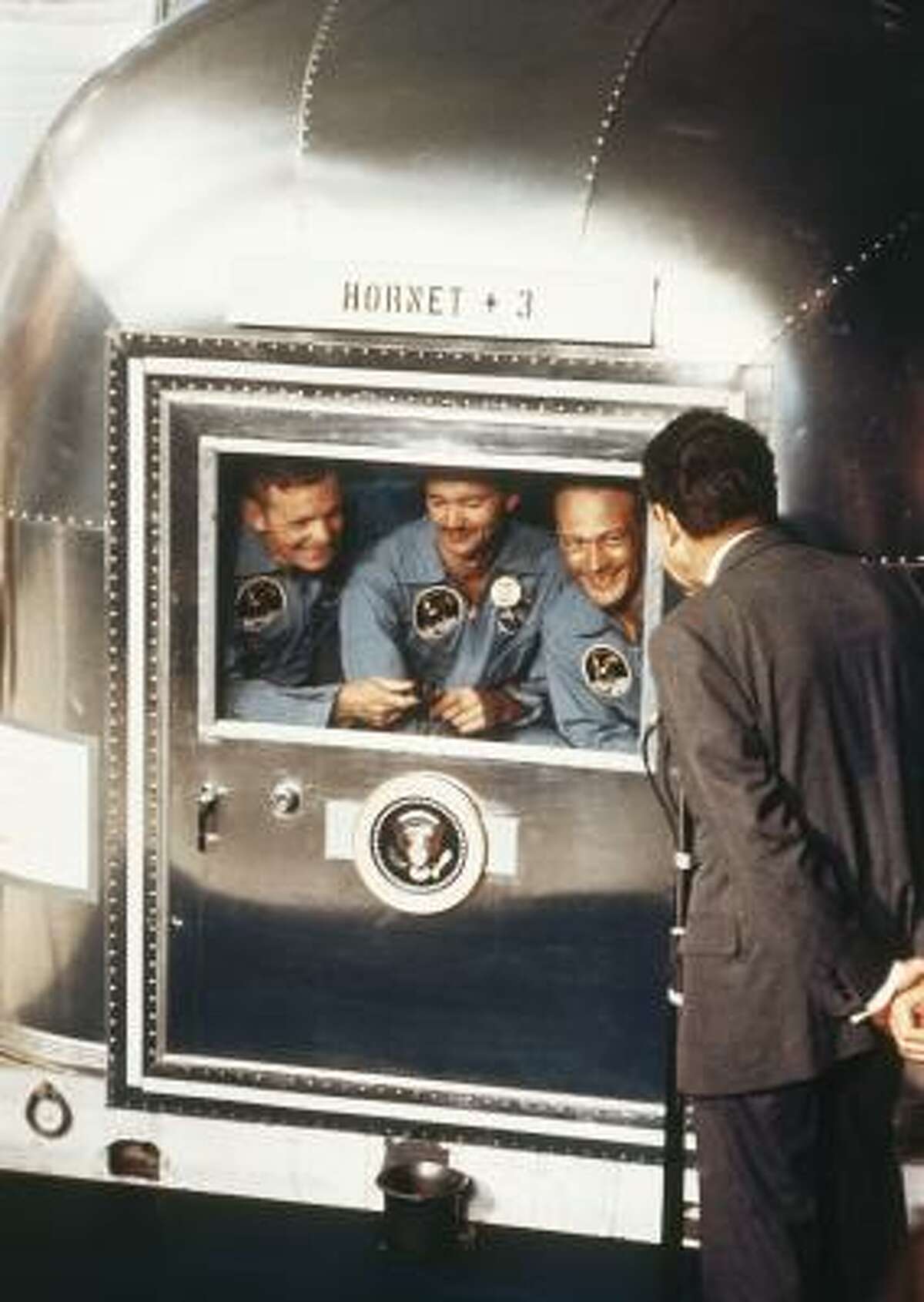 President Richard Nixon greets the Apollo 11 astronauts — Armstrong, left, Collins and Aldrin —on July 24, 1969, in the quarantine van on board the USS Hornet.