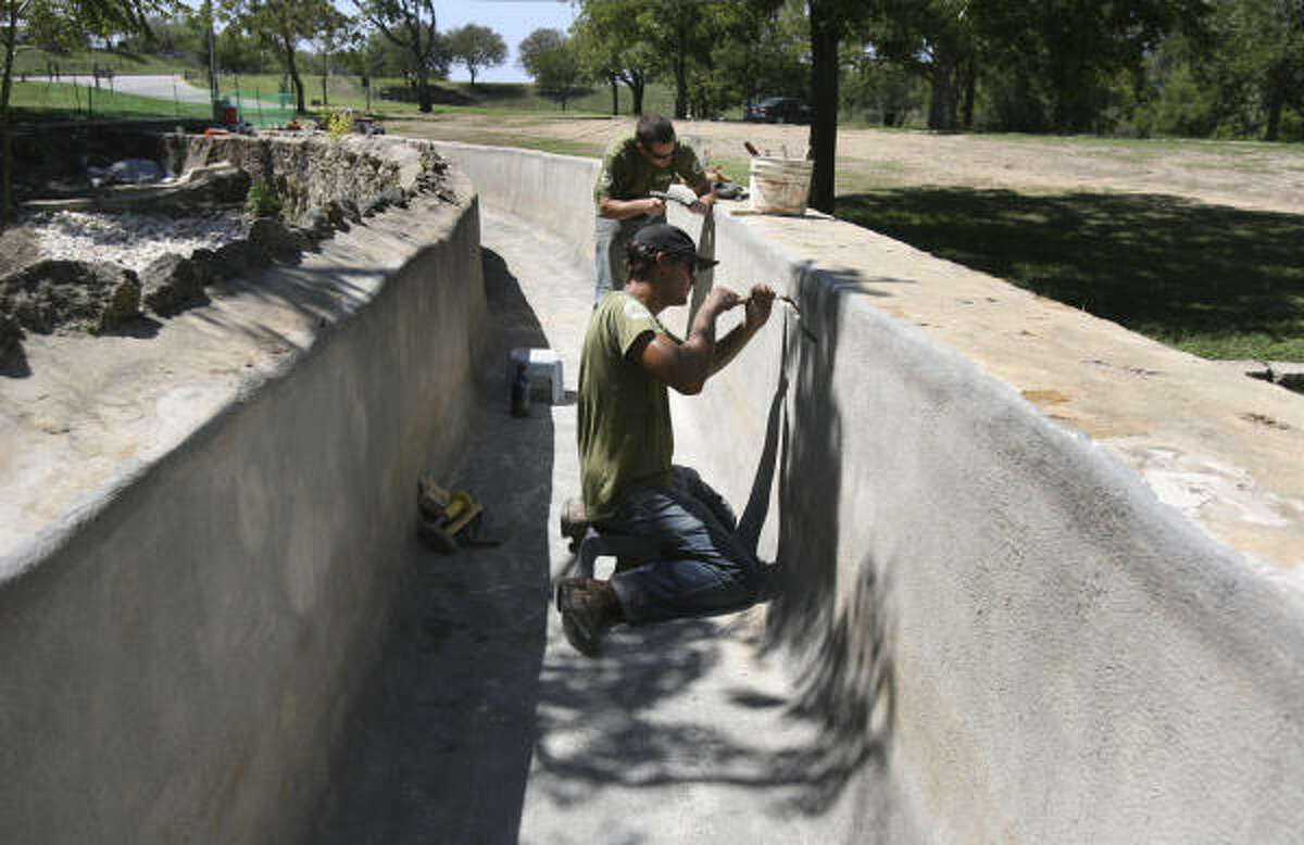 Stephen Kittok, front, and Aaron Braud prepare the Espada Aqueduct for repairs in September.