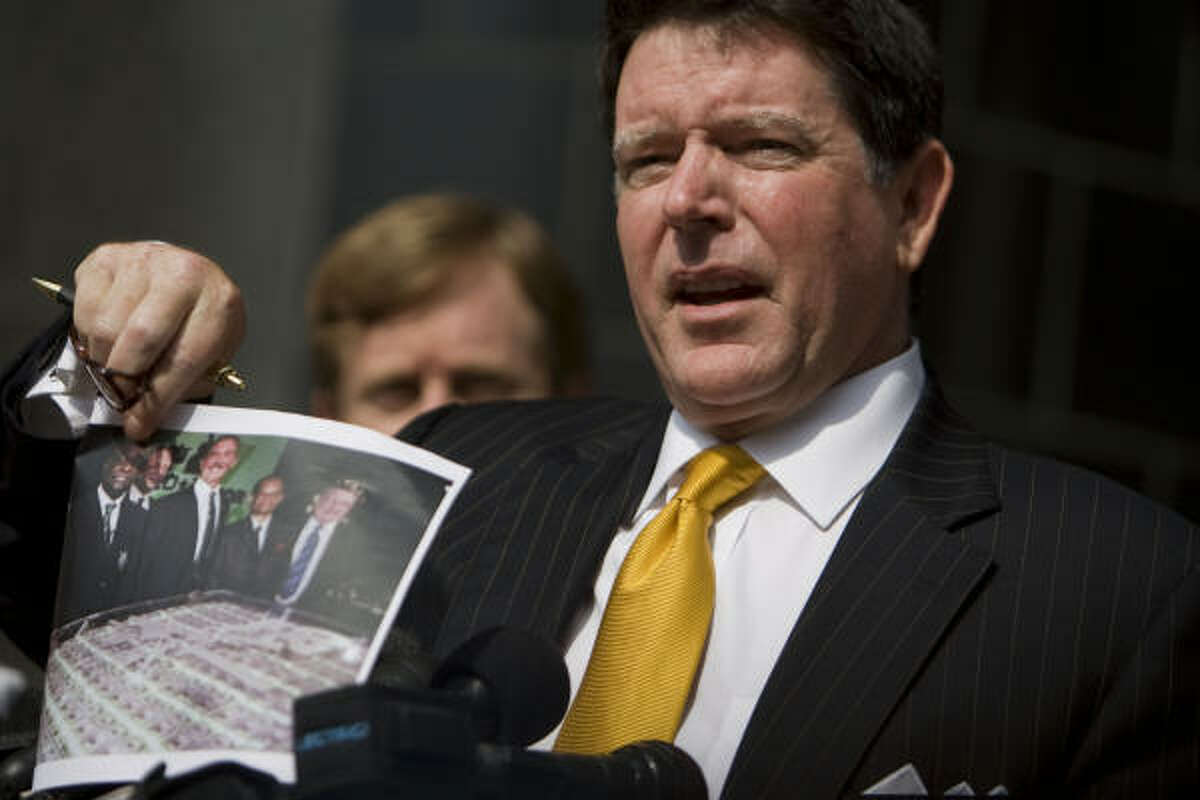 Dan Cogdell, attorney for Laura Pendergest-Holt, the chief investment officer of Stanford Financial Group, holds a photo of other Stanford executives as he says his client is innocent during her arraignment on a criminal charges Friday.