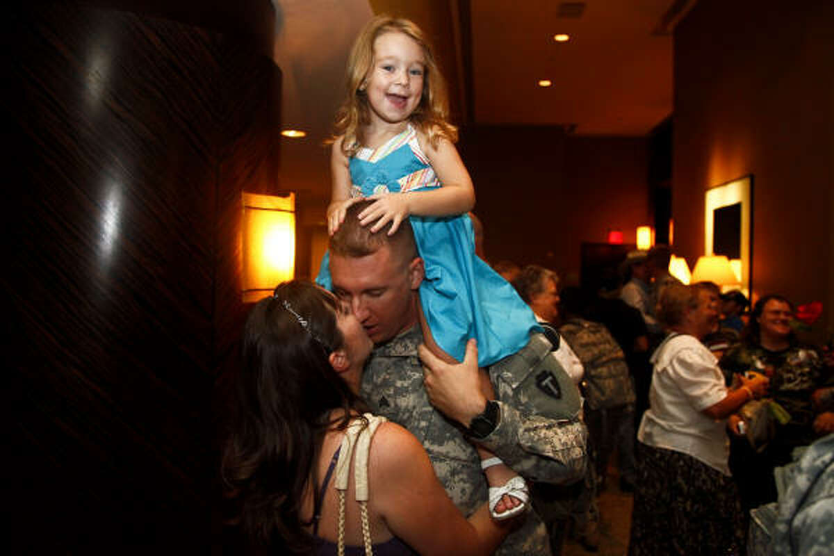 Sgt. Brad Turner holds his daughter, Sara, while greeting his wife, Jennifer, as soldiers from the 712th Military Police Company of the Texas National Guard were welcomed home after a year in Iraq during a downtown ceremony Wednesday. ﻿