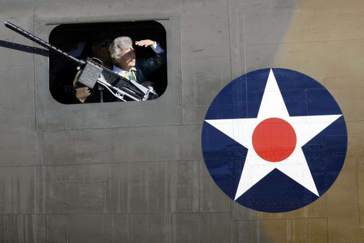 Bea Uhl, standing inside a B-24 bomber, looks out on a F-18 Hornet performing maneuvers at the Wings Over Houston Airshow Saturday. The show at Ellington Airport continues on Sunday.