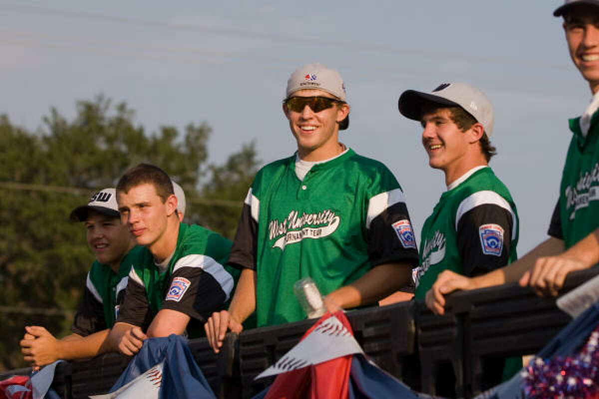 Members of the West U Little League seniors team ride a flatbed truck during their homecoming parade.