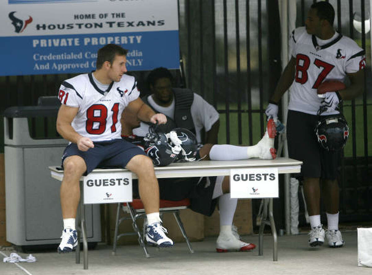 Texans players wait under a check-in tent for their golf cart after practice.