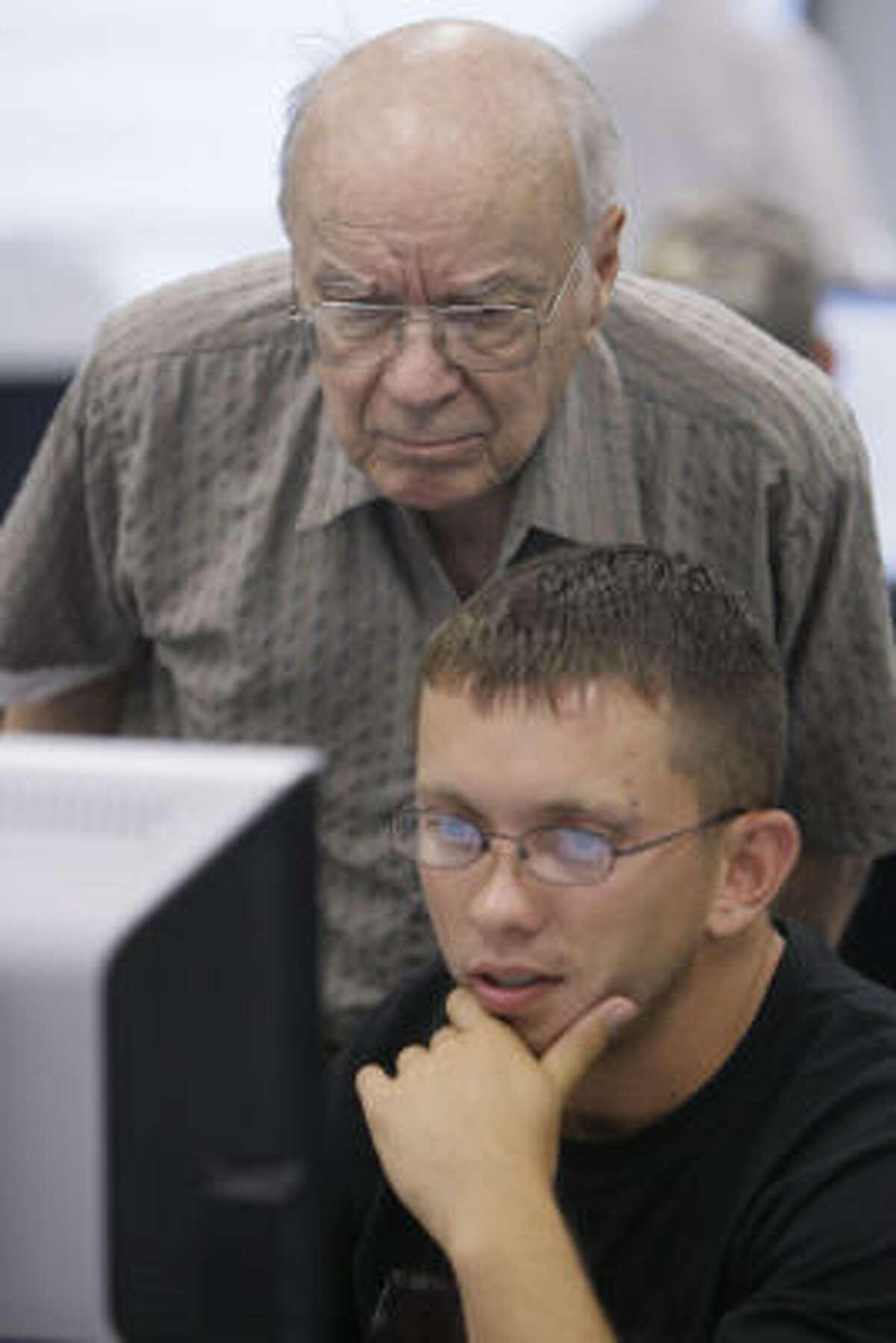 Wayne Hemingway assists Micha Hagan of Cypress at a computer during class.