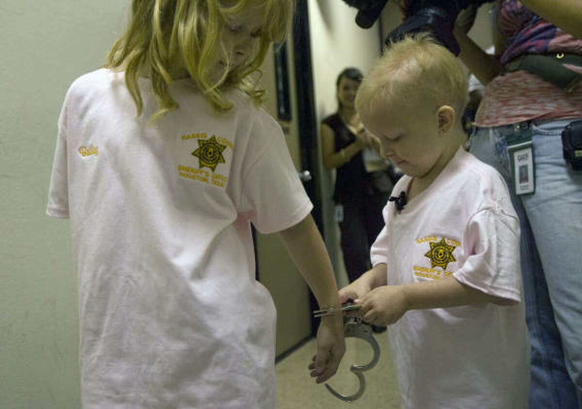 Five-year-old Delaney "Laney" Starcher handcuffs her sister Bailey Starcher as she has her wish to be a cop granted by Harris County Sheriff Adrian Garcia.