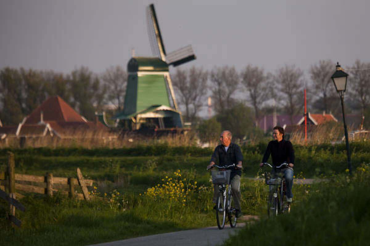 Cyclists ride a path through still-working windmills at Zaanse Schans.