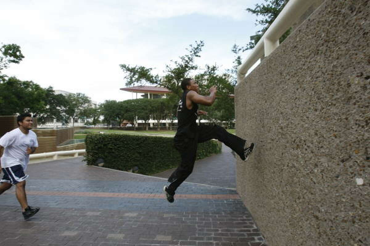 Desmund Mitchell, 22, right, the leader of Houston parkour, demonstrates wall climb as Wilbert Chinchilla, 21, pretends to be an attacker chasing Mitchell, as he performs parkour movements at Tranquility Park.