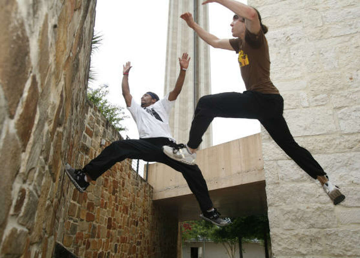 Devin Martin, left, and Sanders launch themselves from one wall up another as the practice the sport under the Tower of The Americas at Hemisfair Plaza in San Antonio.