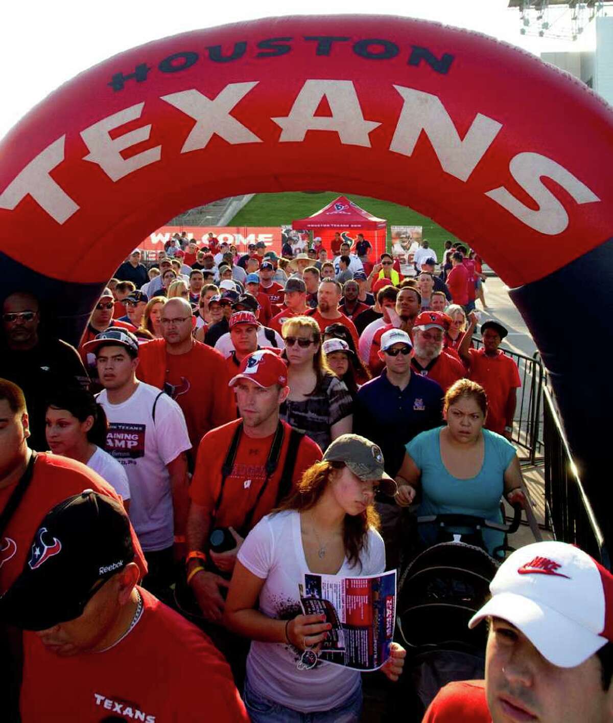 Houston Texans fans walk under an inflatable arch on their way to watch practice during an NFL football training camp Saturday, Aug. 6, 2011, in Houston.