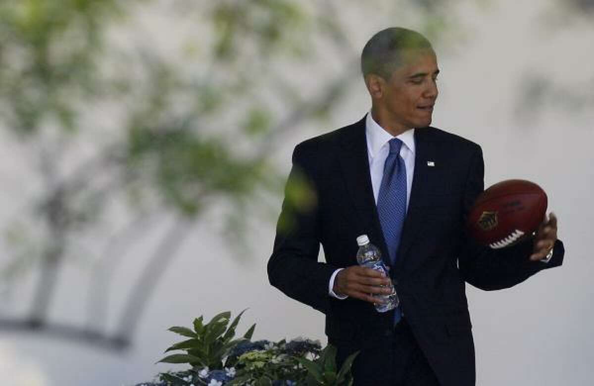 President Obama plays with a football as he walks back to the Oval Office.